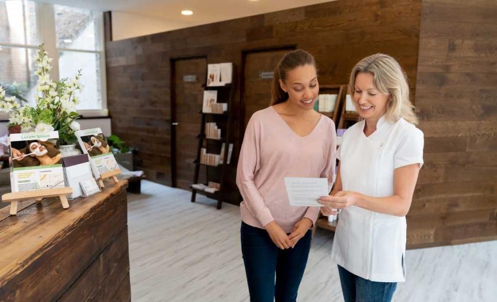 a spa professional showing flyer to female client to introduce body contouring services