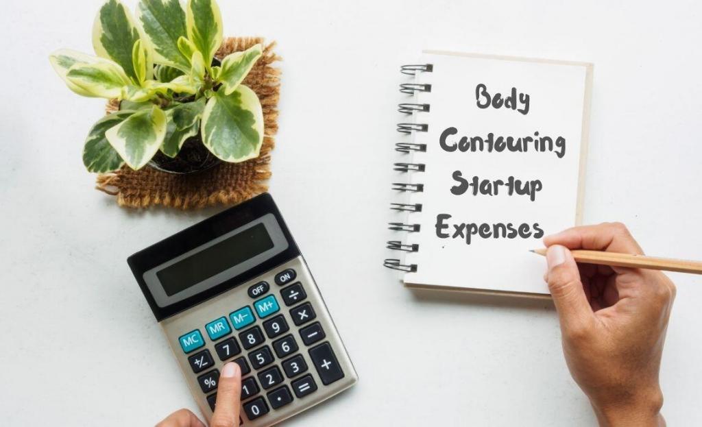 top view of calculator, plant & notepad with body contouring startup expenses to show the cost to start a body contouring business
