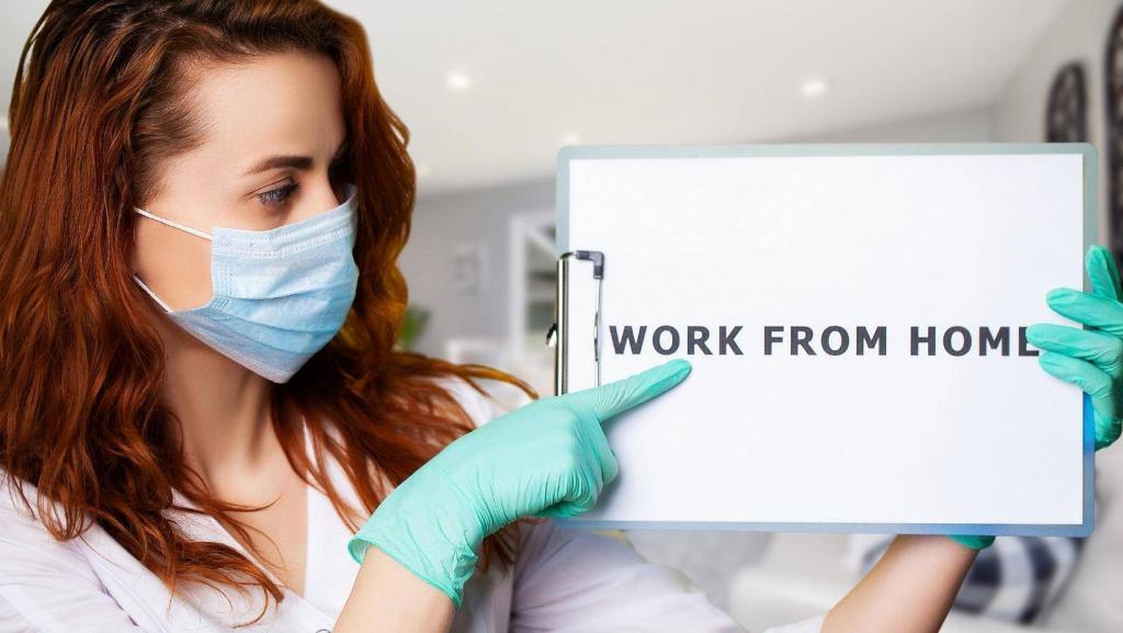 woman with mask and gloves pointing to a sign that says work form home