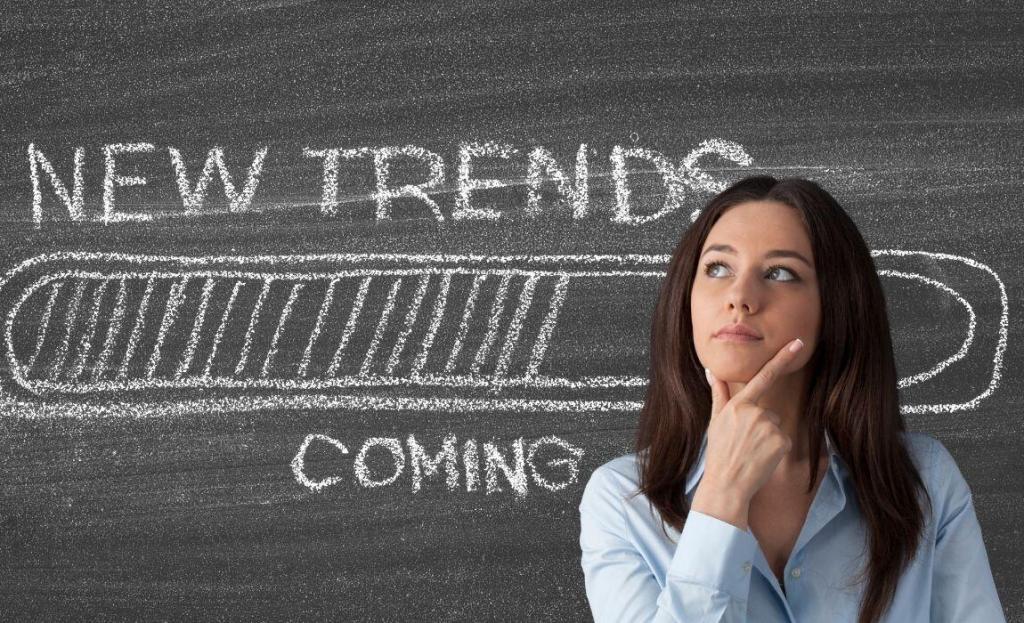 chalk board with "new trends coming" woman with hand to chin looking up