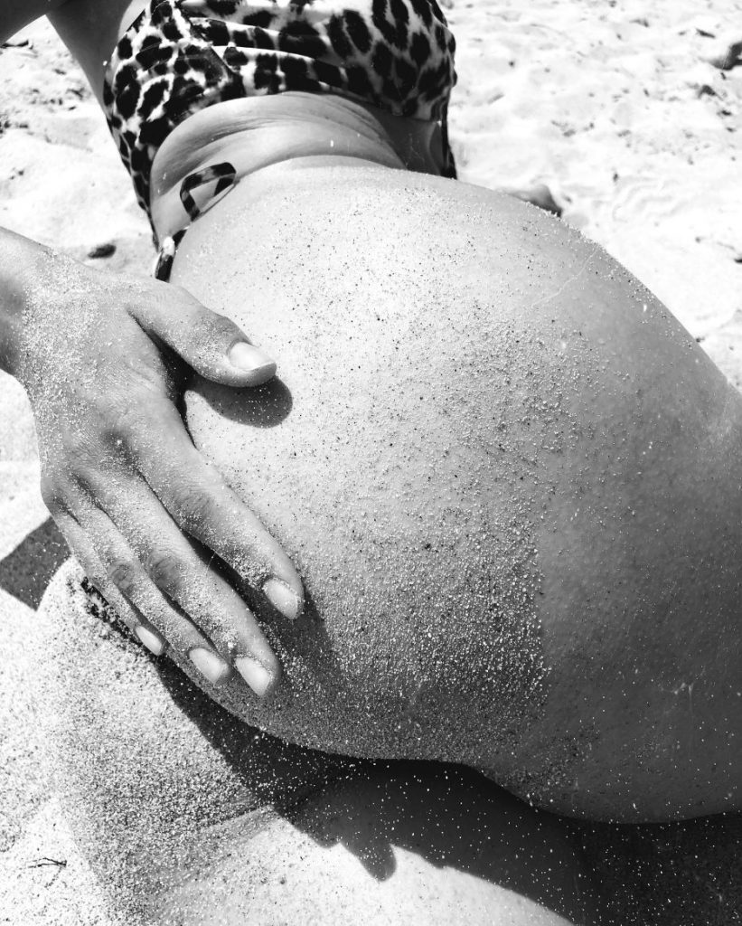 woman's hand on her buttocks in a bikini with sand on beach