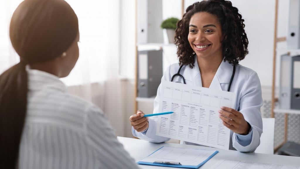 woman smiling pointing out body sculpting treatment plan on paper to another woman