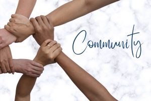 female hands of different color interlocked on the left side of marble background and the word community on the right