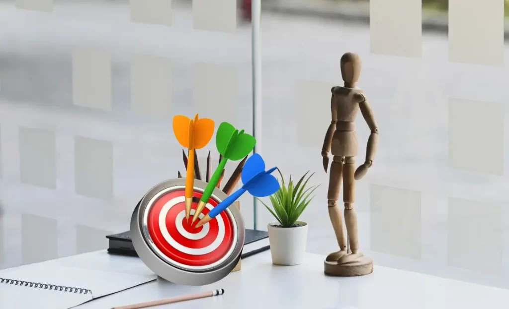 wooden model on desk with a target and darts and notebook to convey to define your target market