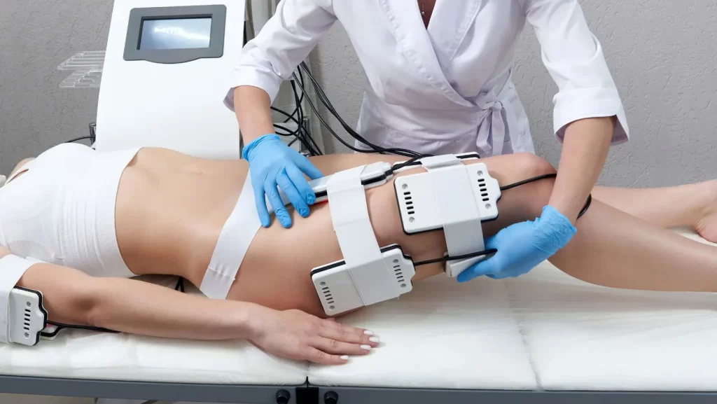body contouring technician applying lipo laser applicators to the thighs of a female client